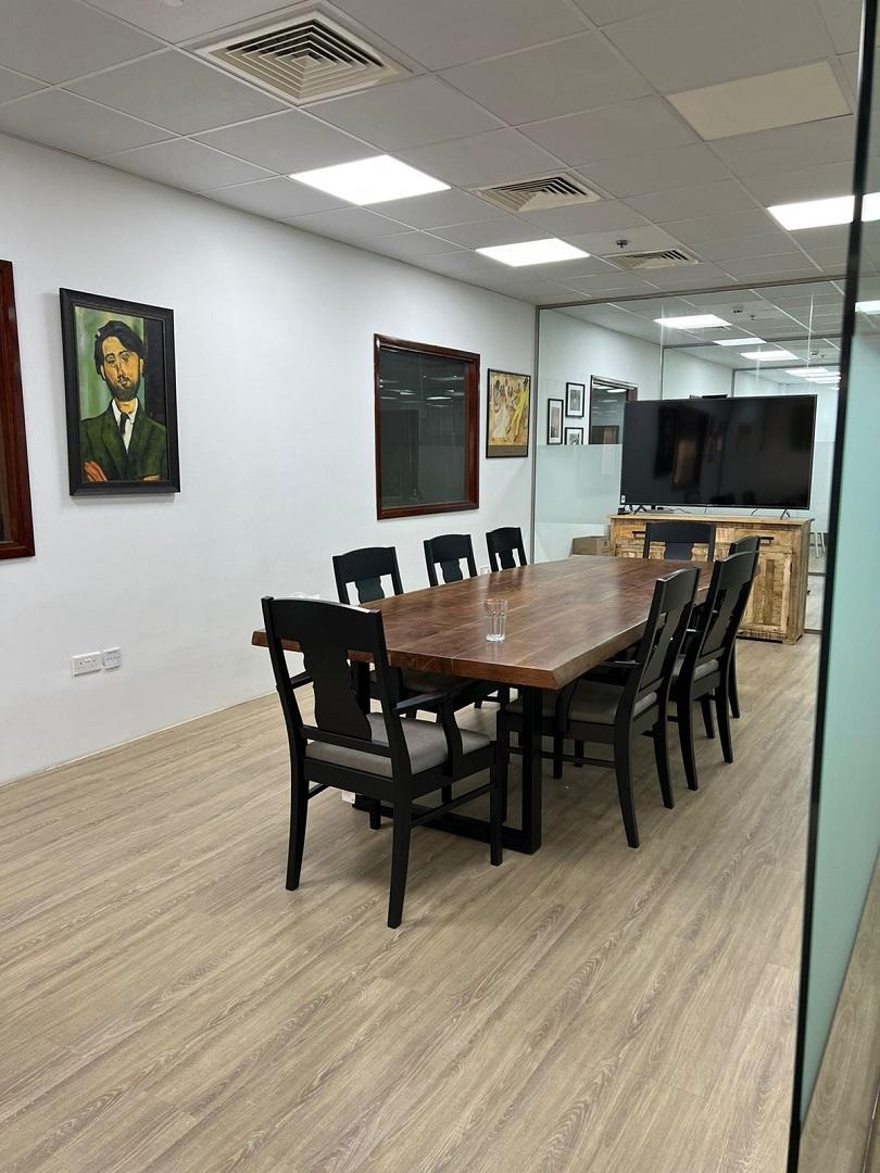 meeting room of an Office with painting hang on the wall and black chairs placed with brown table