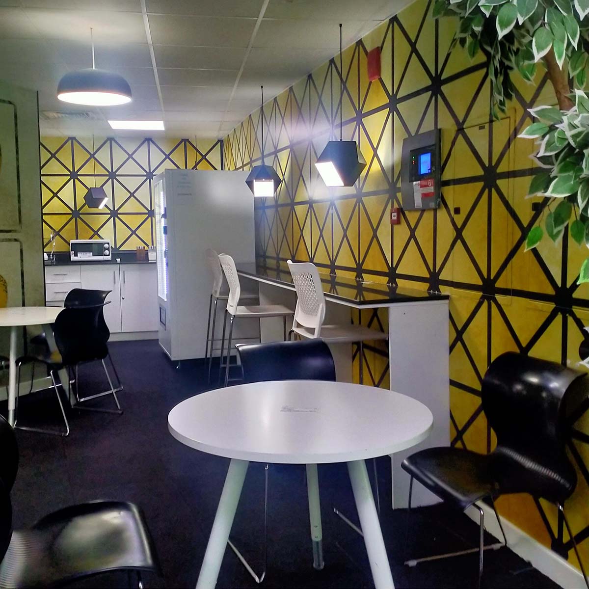 chairs, round table is placed just next to yellow designed wall
